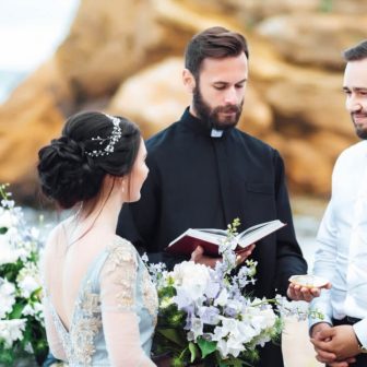 wedding-couple-on-the-ocean-with-a-priest-ELYYJG2.jpg